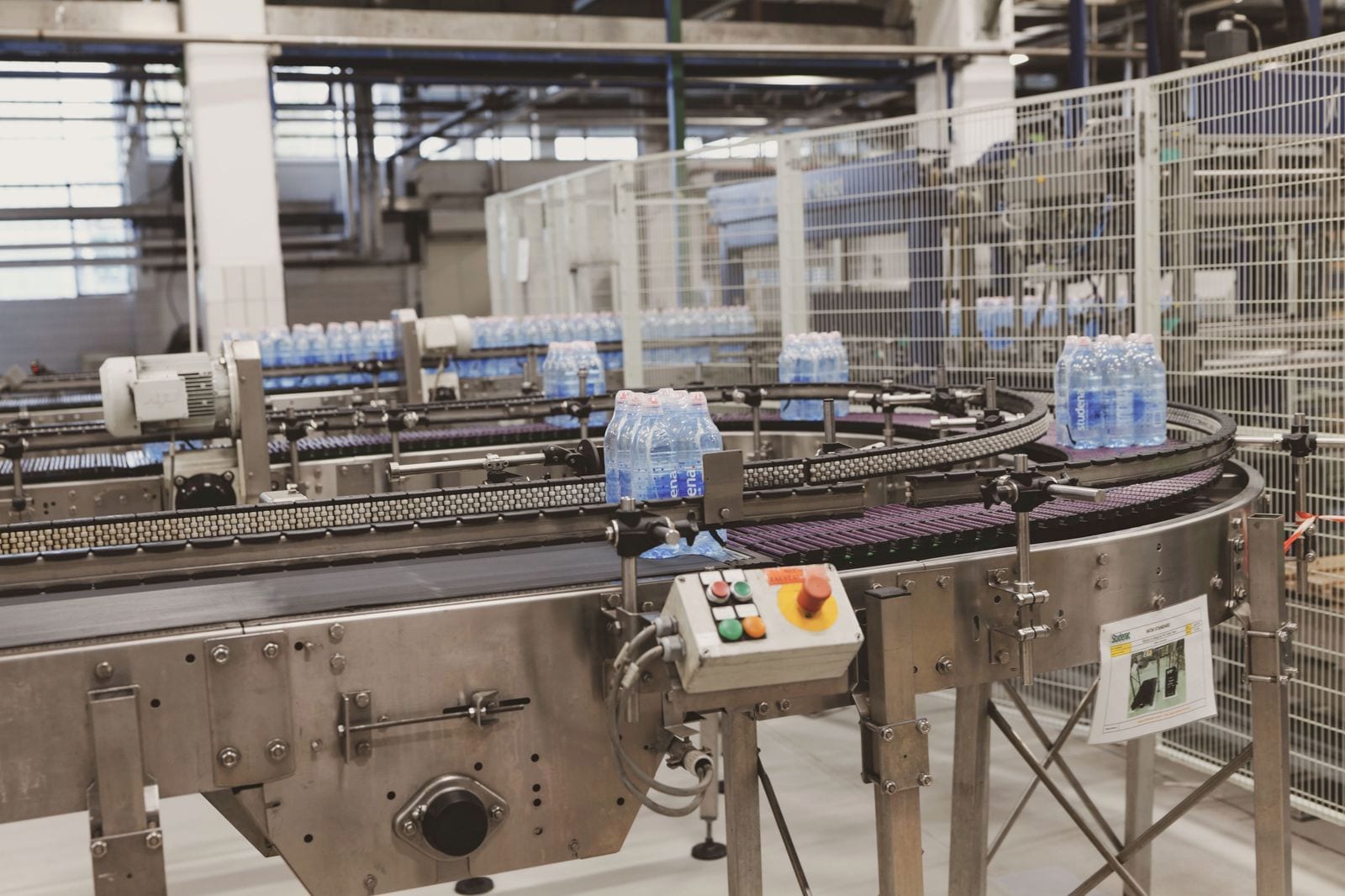 Bottles moving along a curved conveyor past its drive motor