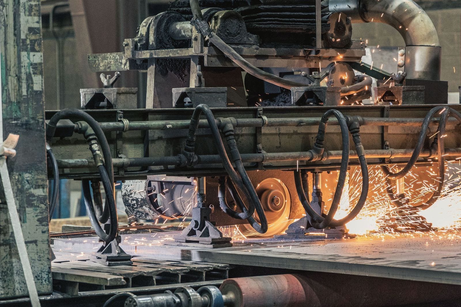 Grinding machine throwing sparks across a steel plate