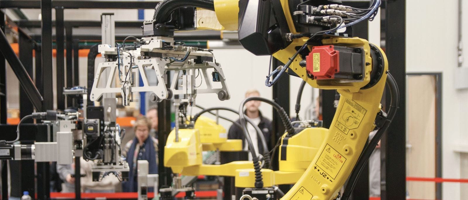 Industrial robot arm with gripper in a manufacturing cell
